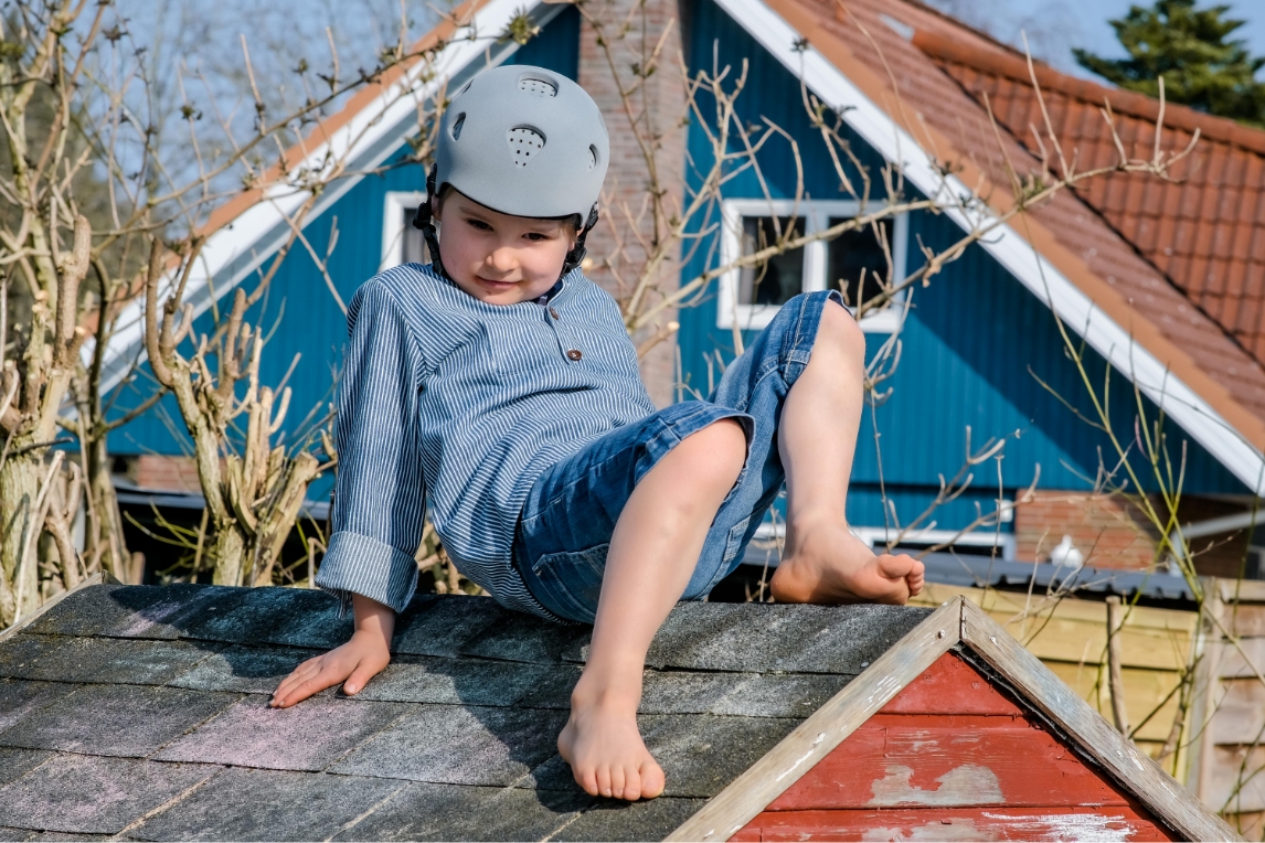 Kind mit Kopforthese klettert auf einem Spielhaus